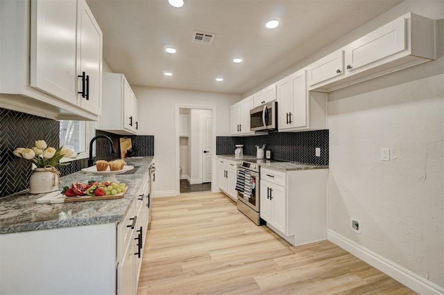 kitchen with white cabinets, light wood-type flooring, stainless steel appliances, and light stone countertops