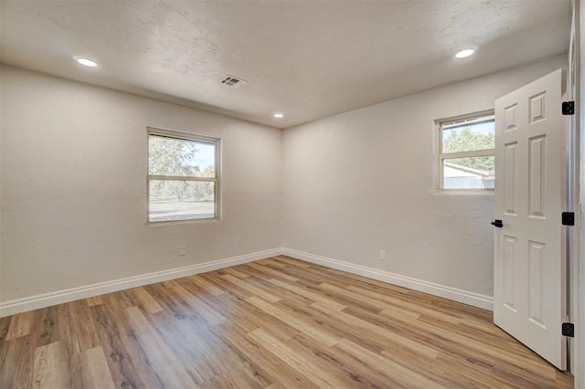 empty room with a healthy amount of sunlight and light hardwood / wood-style flooring