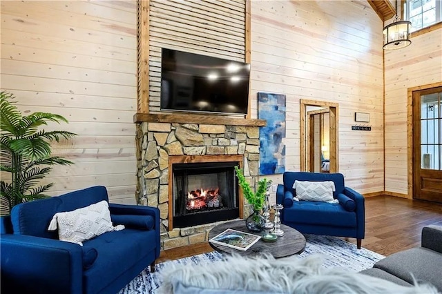 living room featuring wood walls, a stone fireplace, and wood-type flooring