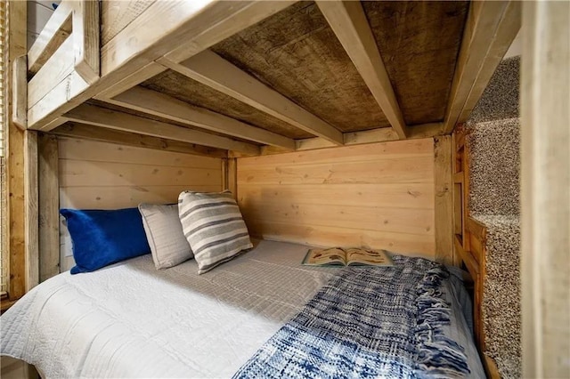 bedroom with wood walls and beam ceiling