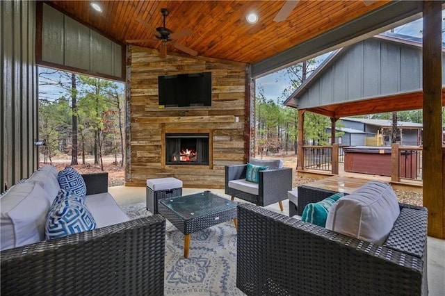 view of patio with an outdoor living space with a fireplace, ceiling fan, and a wooden deck