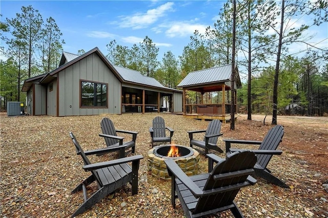 rear view of property with a hot tub, central air condition unit, and a fire pit