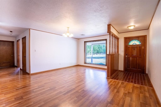 foyer entrance featuring wood-type flooring, a textured ceiling, and an inviting chandelier