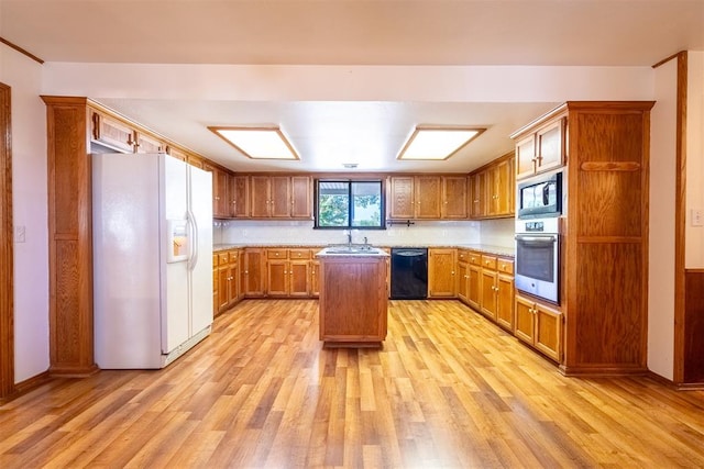 kitchen featuring light hardwood / wood-style floors, sink, black appliances, and a center island