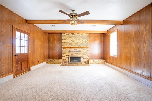 unfurnished living room featuring wooden walls, plenty of natural light, and beam ceiling