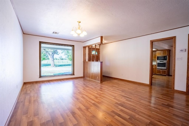 unfurnished living room with an inviting chandelier, hardwood / wood-style floors, and a textured ceiling