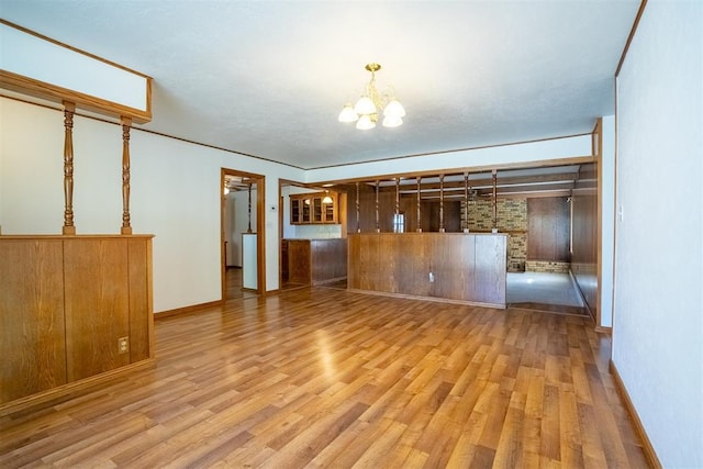 empty room with a notable chandelier and light hardwood / wood-style floors