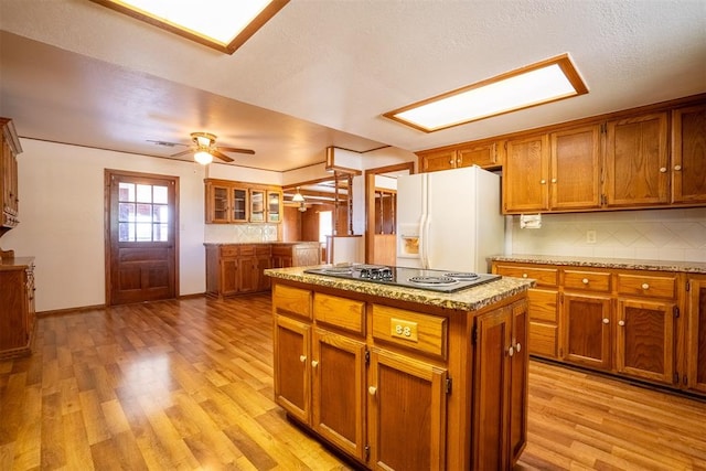 kitchen with black electric cooktop, light hardwood / wood-style flooring, white fridge with ice dispenser, and a kitchen island