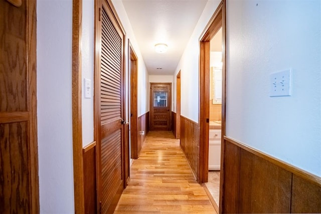 hallway featuring light hardwood / wood-style flooring and wooden walls