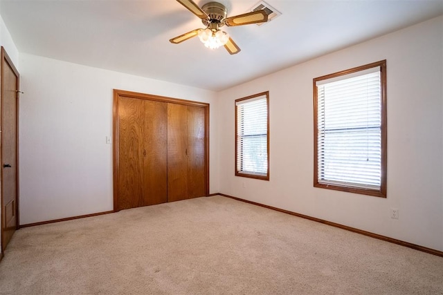 unfurnished bedroom with ceiling fan, light colored carpet, and a closet