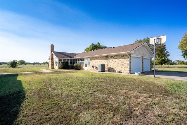 view of front of property featuring cooling unit, a garage, and a front yard