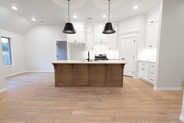 kitchen featuring visible vents, light countertops, light wood-style floors, white cabinetry, and a sink