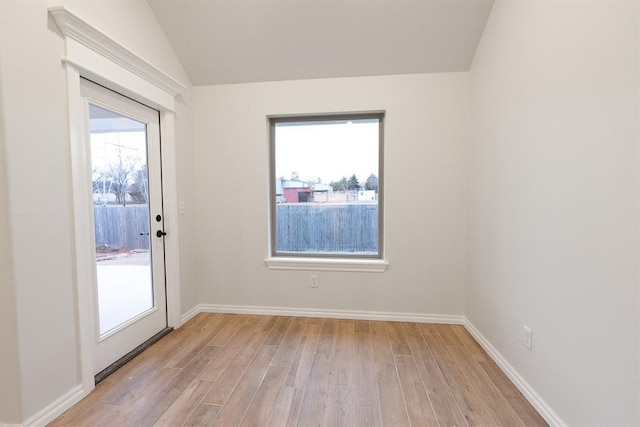 unfurnished room featuring lofted ceiling, baseboards, and light wood-style floors