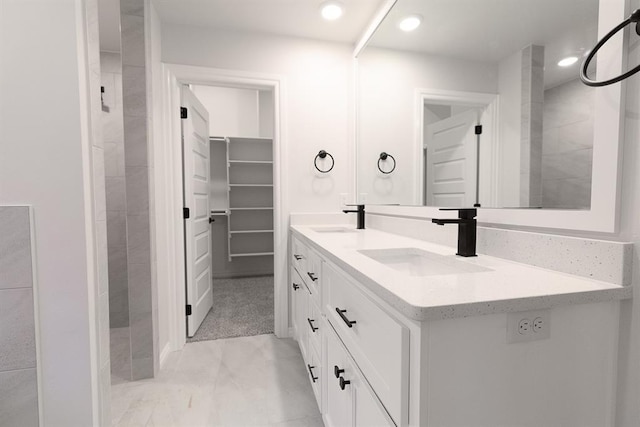 full bath with a walk in closet, a sink, recessed lighting, and double vanity