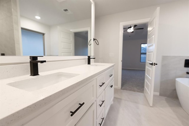 full bathroom with double vanity, a freestanding tub, a sink, and visible vents