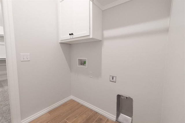 laundry room with hookup for a washing machine, cabinet space, light wood-style floors, and baseboards