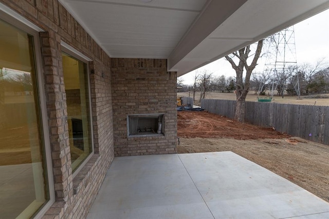 view of patio / terrace with an outdoor brick fireplace and fence