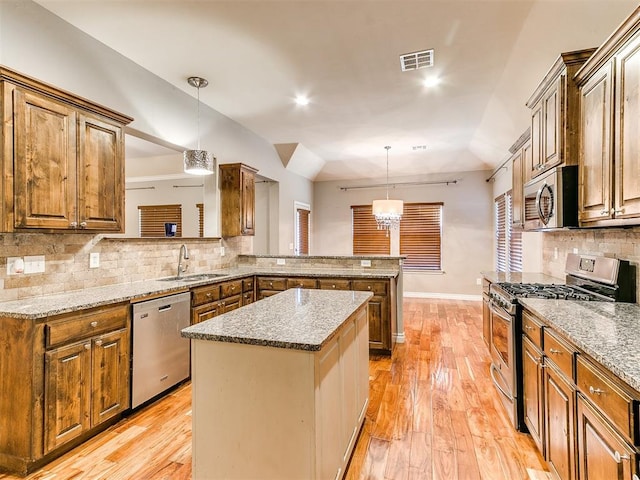 kitchen featuring a center island, sink, hanging light fixtures, stainless steel appliances, and kitchen peninsula