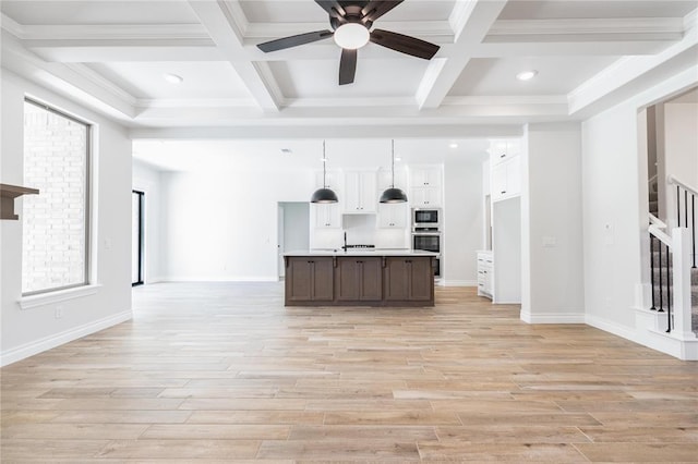14001 Birch Ln, Edmond, OK 73049 - kitchen featuring built in microwave, coffered ceiling, open floor plan, light countertops, and light wood-style flooring