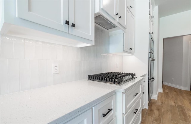14001 Birch Ln, Edmond, OK 73049 - kitchen featuring appliances with stainless steel finishes, white cabinets, backsplash, light wood finished floors, and light stone counters