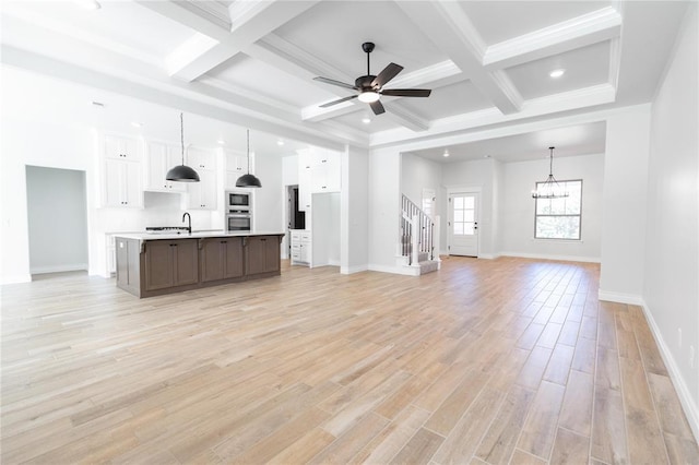 14001 Birch Ln, Edmond, OK 73049 - unfurnished living room featuring coffered ceiling, a chandelier, beamed ceiling, light wood-type flooring, and a ceiling fan