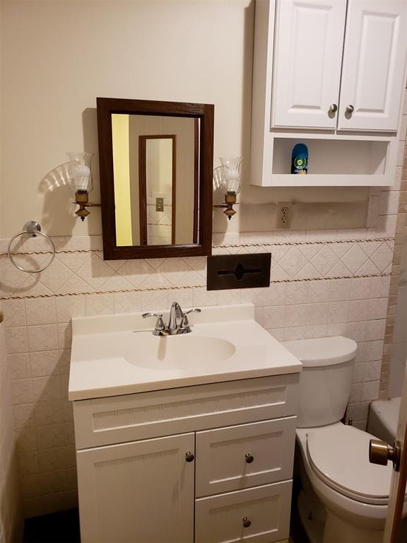 bathroom with vanity, toilet, and tile walls