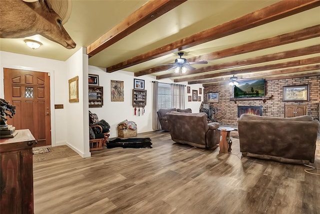 living room featuring a fireplace, hardwood / wood-style flooring, ceiling fan, and brick wall