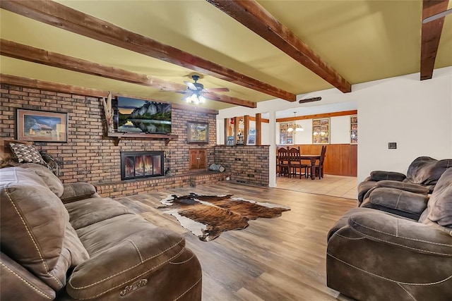 living room with beamed ceiling, ceiling fan, light hardwood / wood-style floors, and a brick fireplace