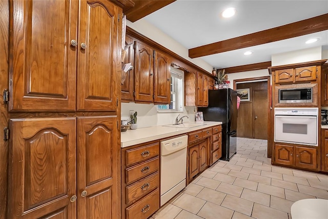 kitchen featuring beam ceiling, white appliances, and sink