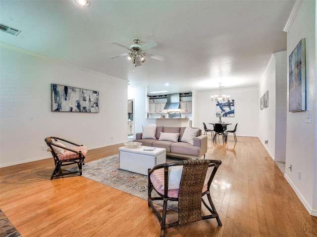 living room featuring hardwood / wood-style flooring, ceiling fan with notable chandelier, and crown molding