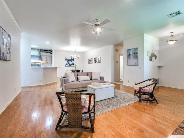 living room featuring ceiling fan with notable chandelier, light hardwood / wood-style floors, and ornamental molding