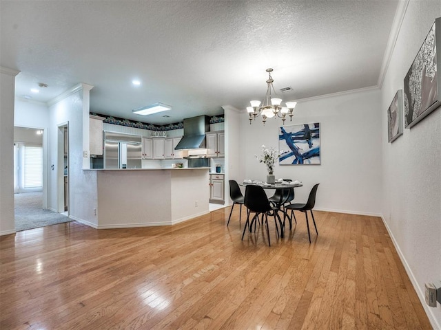 dining space with a textured ceiling, light wood-type flooring, ornamental molding, and a chandelier