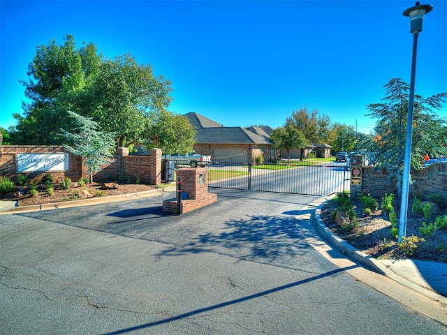 view of street with a gate, curbs, and a gated entry