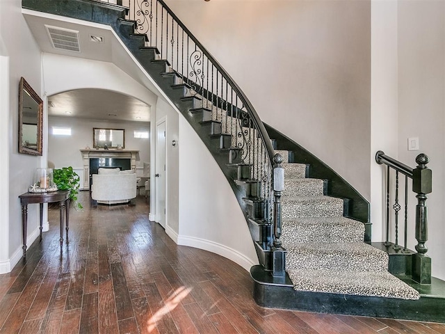 staircase featuring a towering ceiling and wood-type flooring