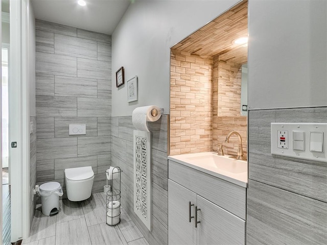 bathroom featuring vanity, tile walls, and toilet