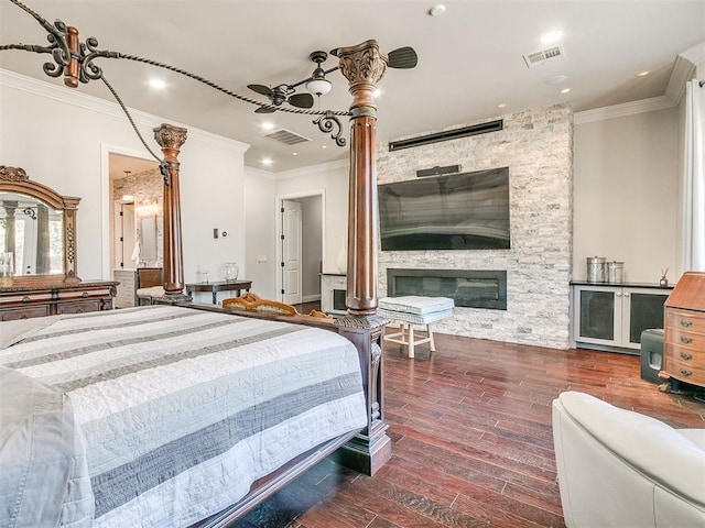 bedroom featuring dark hardwood / wood-style flooring, a stone fireplace, ceiling fan, and ornamental molding