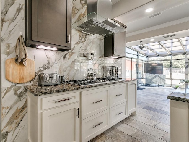 kitchen with white cabinets, stainless steel gas stovetop, crown molding, and island exhaust hood