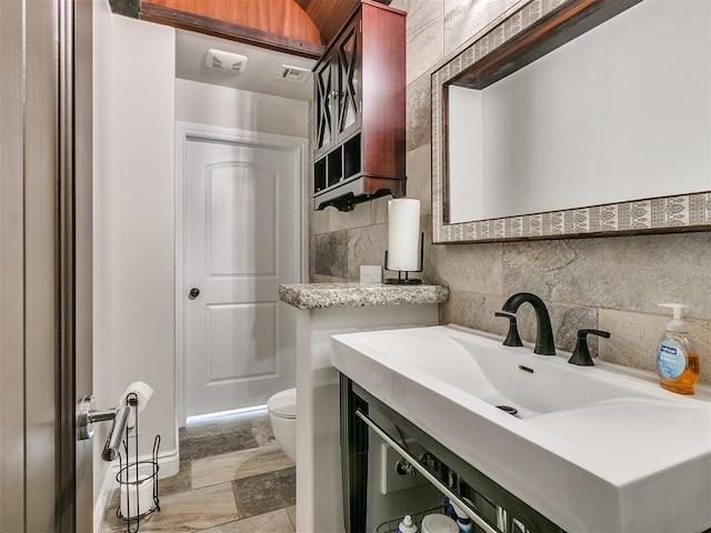 bathroom with vanity, toilet, and tile walls