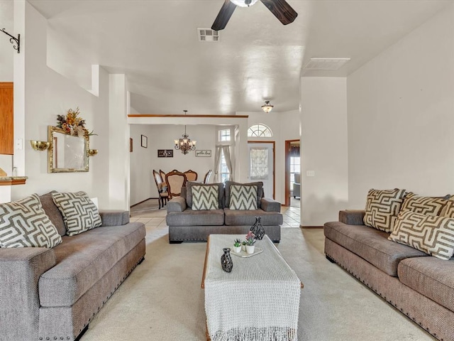 carpeted living room featuring ceiling fan with notable chandelier