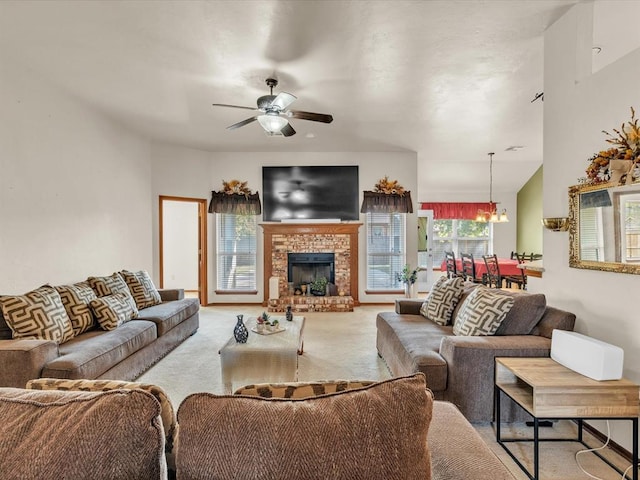 living room featuring a fireplace, light colored carpet, and ceiling fan with notable chandelier