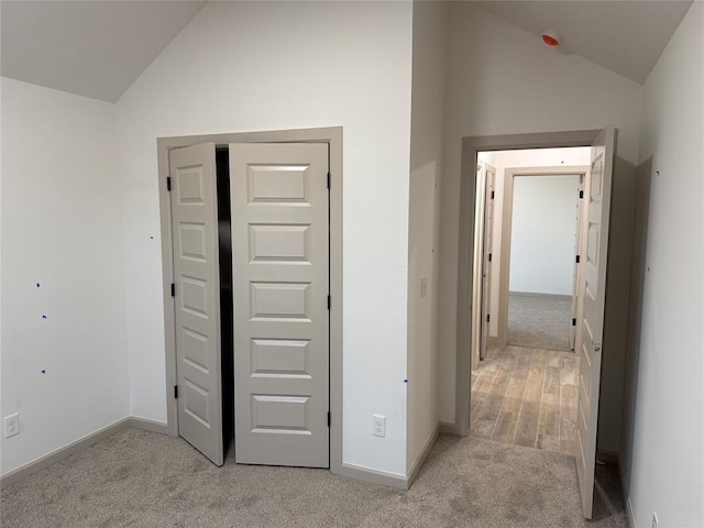 corridor featuring light carpet and lofted ceiling