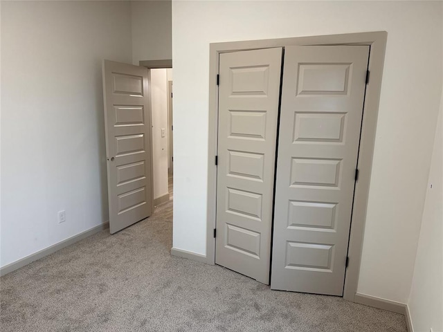 unfurnished bedroom featuring light carpet and a closet