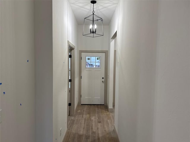 corridor featuring hardwood / wood-style floors, a towering ceiling, and a notable chandelier