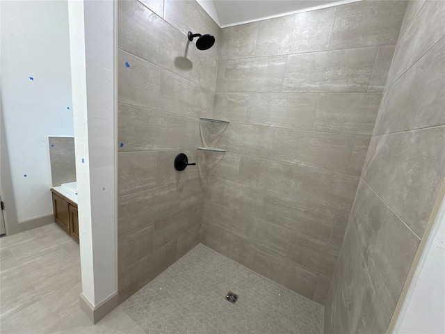 bathroom with tiled shower and vanity