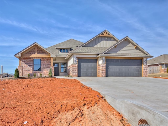 view of front of house with brick siding, roof with shingles, an attached garage, board and batten siding, and driveway