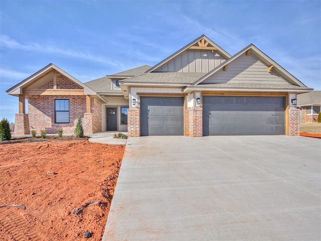 view of front of home with brick siding, a shingled roof, concrete driveway, board and batten siding, and a garage