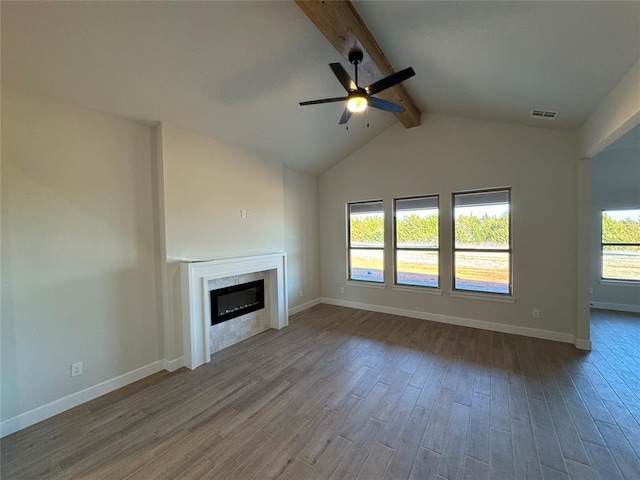 unfurnished living room with vaulted ceiling with beams, visible vents, a glass covered fireplace, wood finished floors, and baseboards