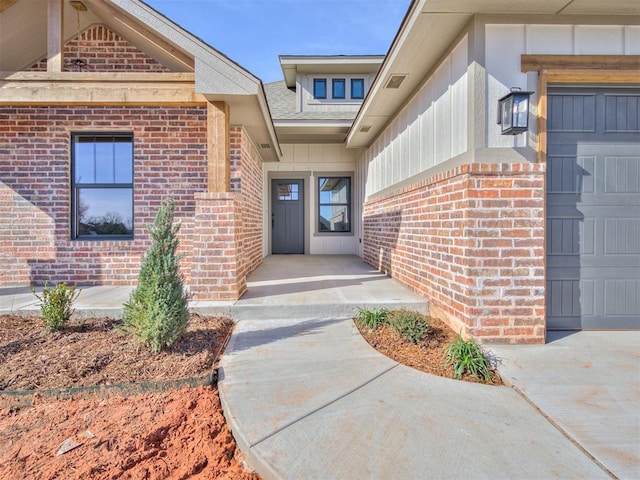 property entrance with a garage, brick siding, and board and batten siding