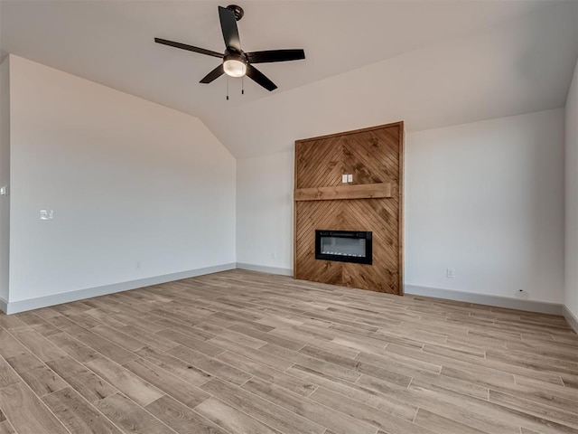 unfurnished living room with light wood-style floors, a large fireplace, and vaulted ceiling