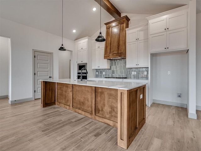 kitchen featuring tasteful backsplash, lofted ceiling with beams, custom range hood, light countertops, and a sink